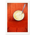 Kunstfotografi av latte i glass med metallsugerør, sett ovenfra mot rød designstol i tekstil. Kaffeskummet skaper abstrakte former som refererer til tradisjonen med å spå i kaffe.