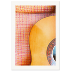Kunstfotografi av akustisk gitar mot rutet retrotekstil i varme oransje, rosa og gule toner. Nærstudie av treverk, mønster og materialkontraster.